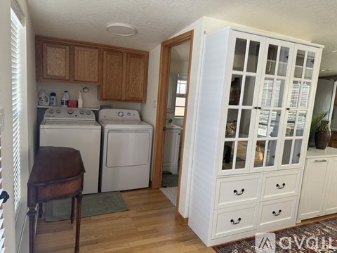 A kitchen with a white cabinet and a brown chair.