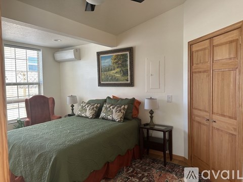 A bedroom with a bed, a chair, and a painting on the wall.