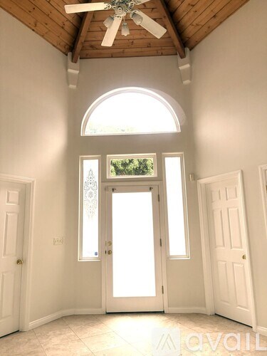 A room with a ceiling fan and a large arched window.