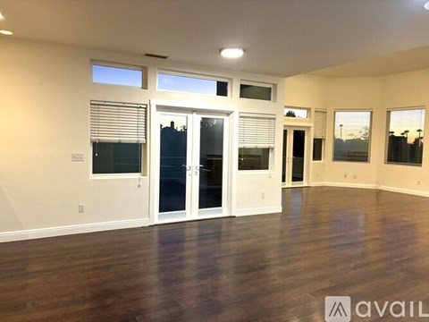 A spacious room with wooden floors and large windows.
