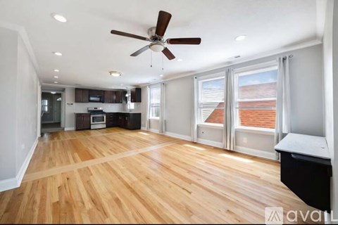 A spacious room with wooden floors and a ceiling fan.
