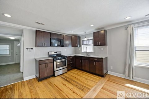 A kitchen with wooden floors and dark brown cabinets.