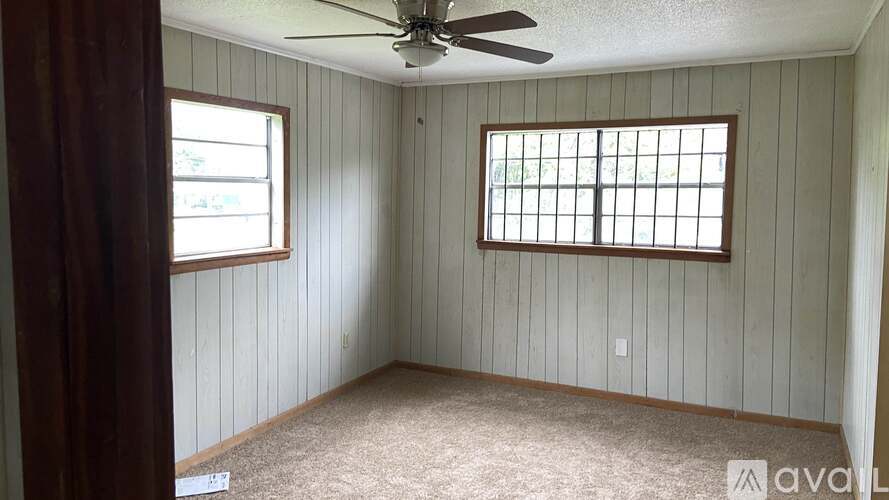 A room with a ceiling fan and two windows.