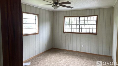 A room with a ceiling fan and two windows.