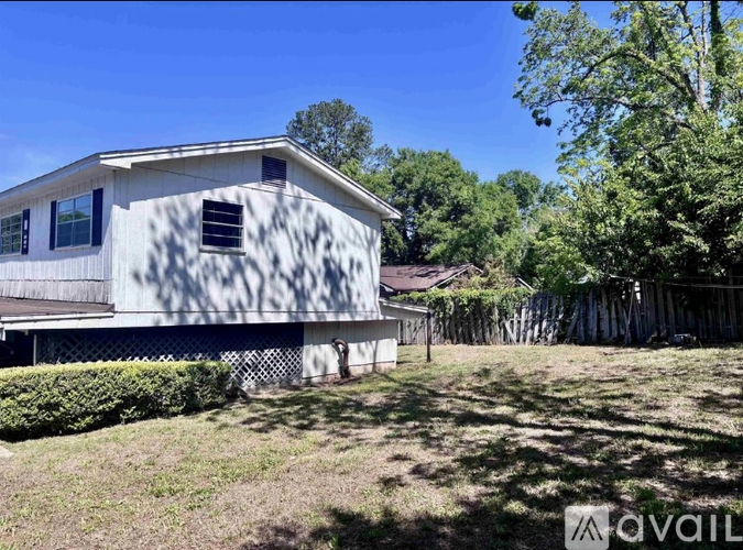 A house with a flag on the front is surrounded by a fence and trees.