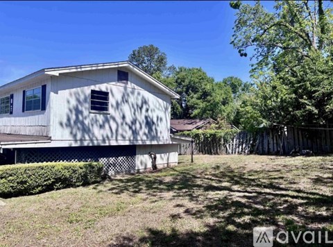 A house with a flag on the front is surrounded by a fence and trees.