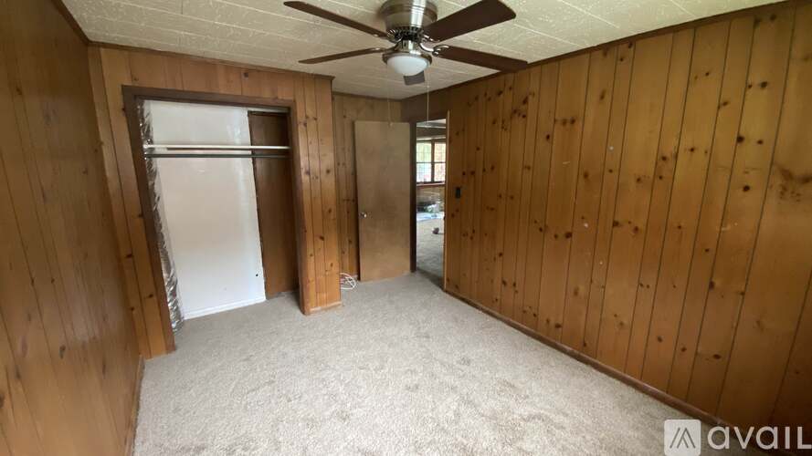 A room with wooden walls and a ceiling fan.