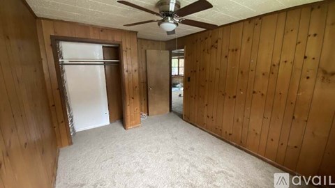 A room with wooden walls and a ceiling fan.