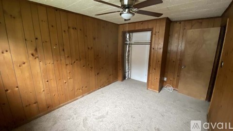 A room with wooden walls and a ceiling fan.