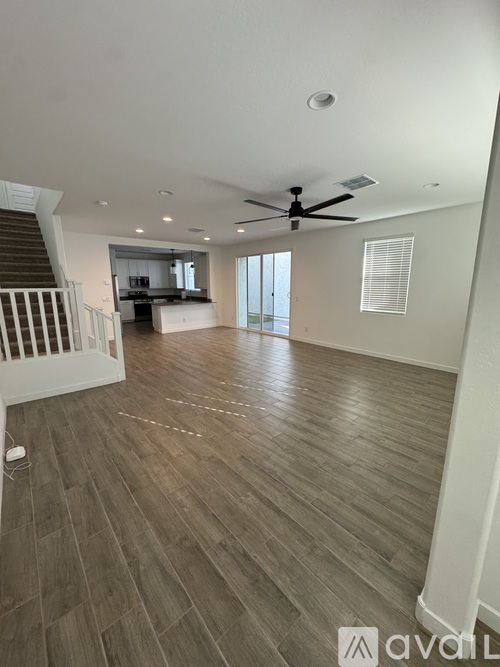 A spacious room with wooden flooring and a ceiling fan.