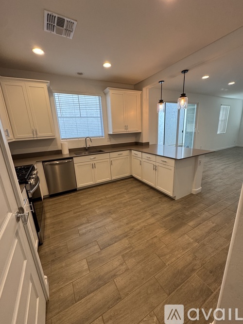 A kitchen with white cabinets and a wooden floor.