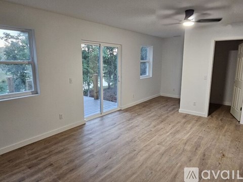 A spacious room with wood flooring and a sliding glass door leading outside.
