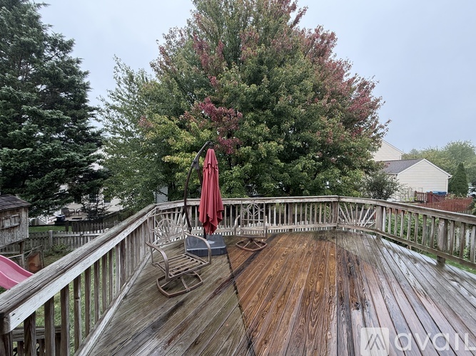 A wooden deck with a red umbrella and a bench.
