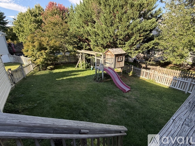 A backyard with a wooden deck and a red slide.