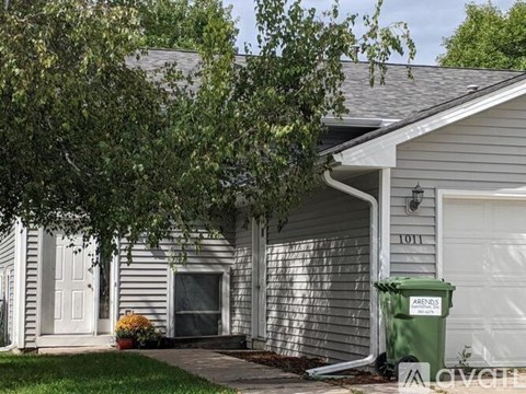 A house with a grey siding and a white door is shown.