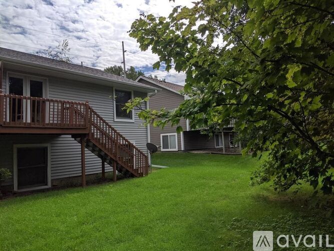 A house with a deck and a tree in front.