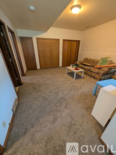 A living room with a couch, a coffee table, and a refrigerator.