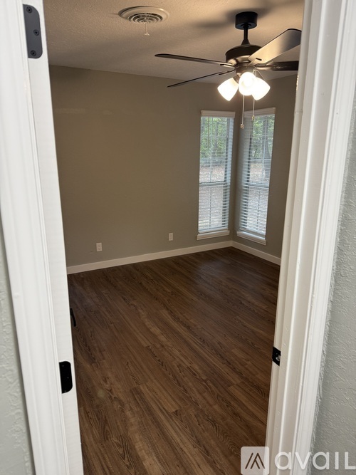 A room with a ceiling fan and wooden flooring.