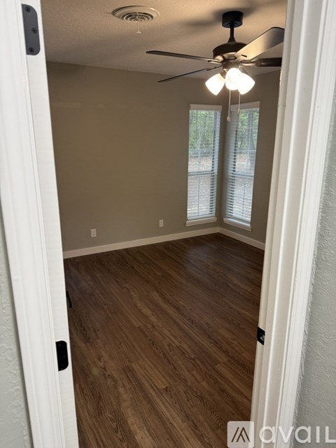 A room with a ceiling fan and wooden flooring.