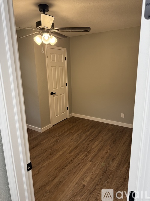 A room with a ceiling fan and wooden flooring.