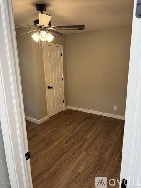 A room with a ceiling fan and wooden flooring.