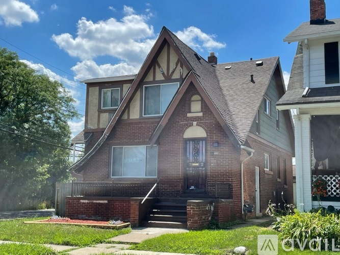 A house with a brown brick exterior and a large front porch.