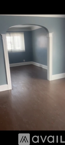 A room with a wooden floor and a window with blinds.