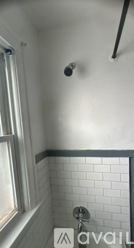 A bathroom with a shower head and a window.