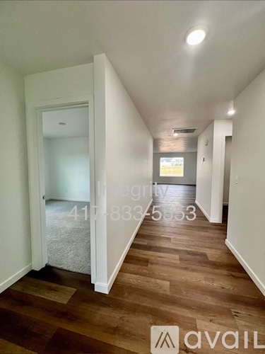 A hallway with wood flooring and white walls.