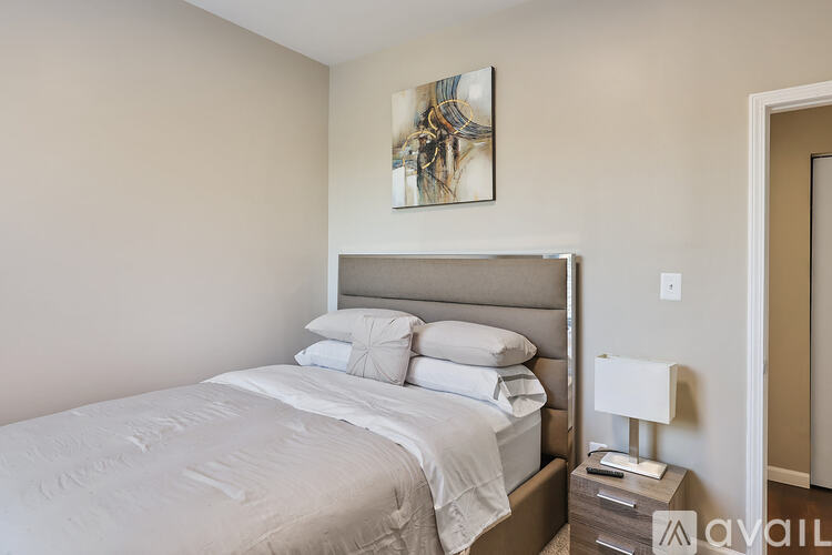 A bedroom with a large bed and a painting on the wall.
