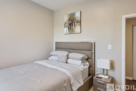 A bedroom with a large bed and a painting on the wall.