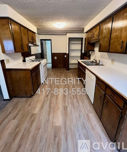 A kitchen with wood floors and cabinets, a stove, and a sink.