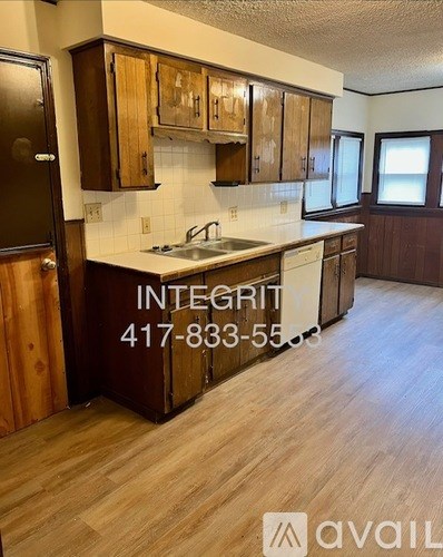 A kitchen with wooden cabinets and a countertop with a sink.