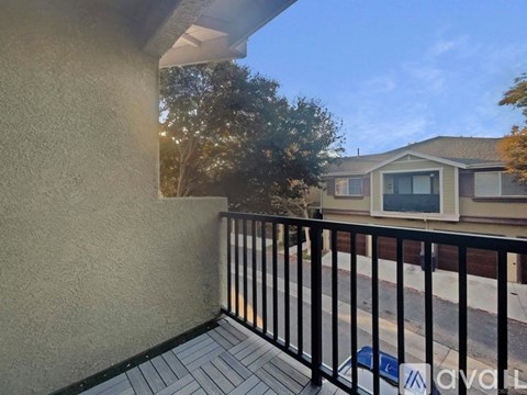 A balcony with a black railing and a view of a house and trees.