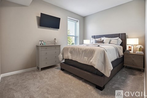 A bedroom with a large bed, a nightstand, and a TV mounted on the wall.