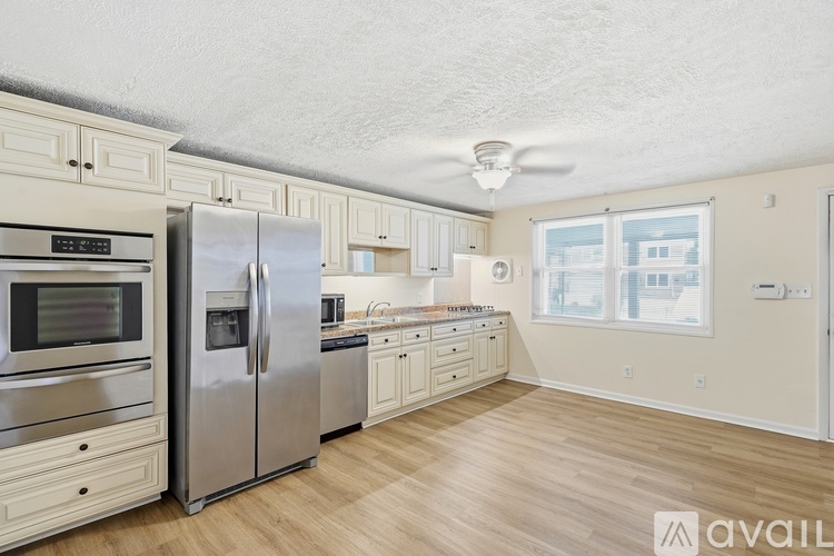 A kitchen with a refrigerator, oven, microwave, and wooden floors.