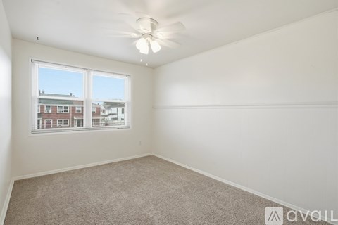 A room with a carpeted floor and a window showing a view of buildings outside.