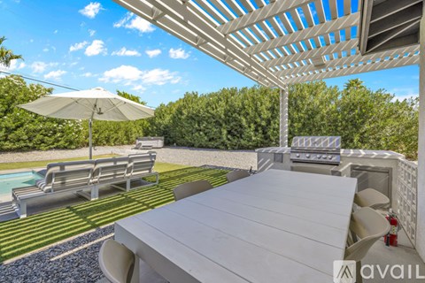 A patio with a table and chairs overlooking a pool.