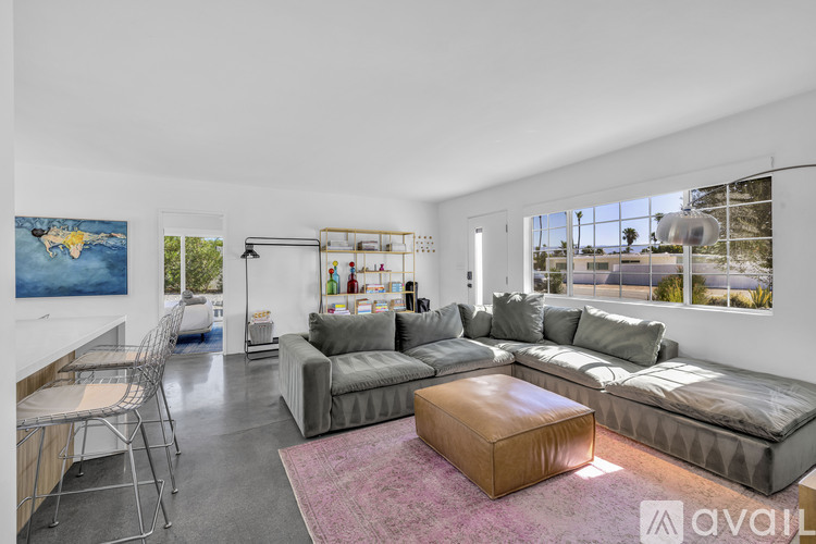 A living room with a grey couch and a pink rug.