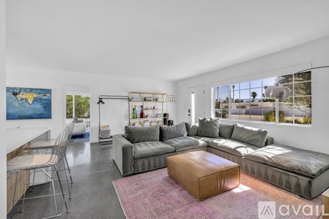 A living room with a grey couch and a pink rug.