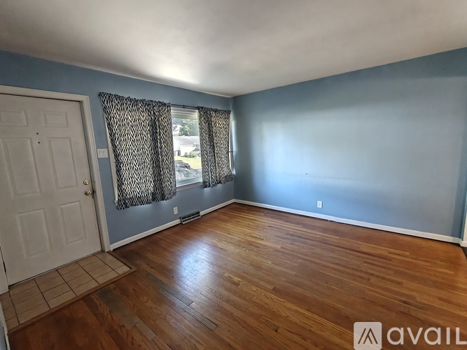 A room with wooden flooring and a door leading to another room.