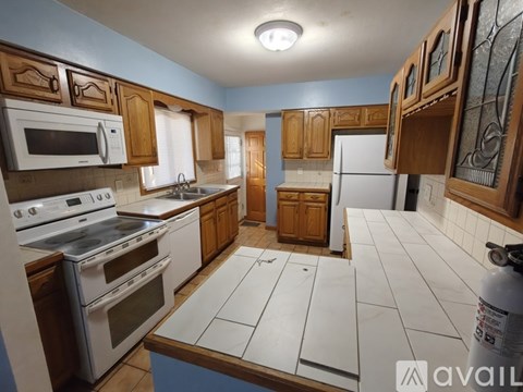 A kitchen with white appliances and wooden cabinets.