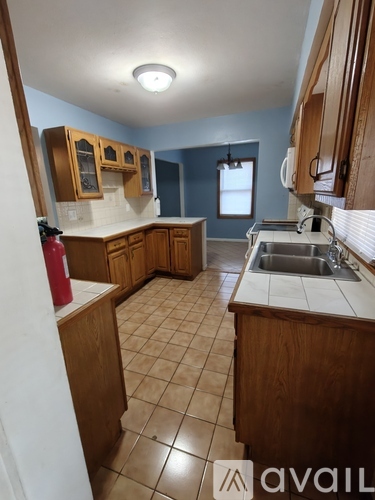 A kitchen with wooden cabinets and a tiled floor.