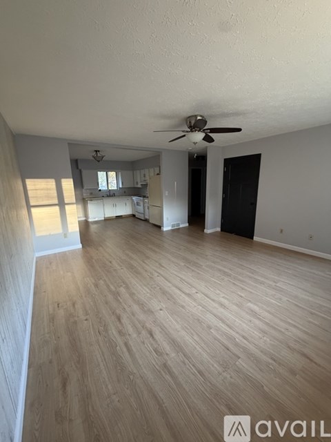 A spacious room with wooden flooring and a ceiling fan.