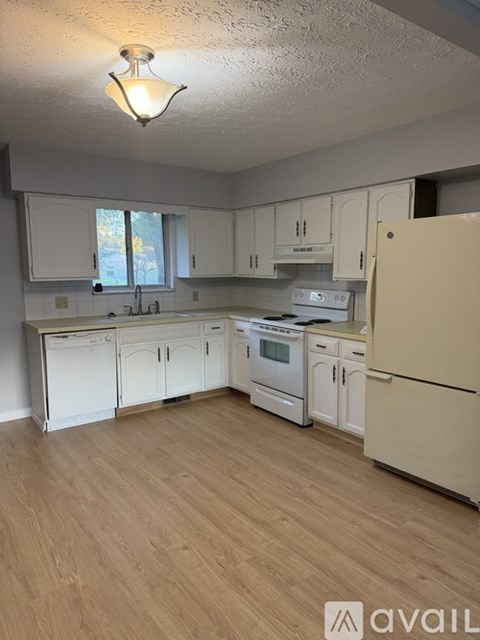 A kitchen with white cabinets and appliances.