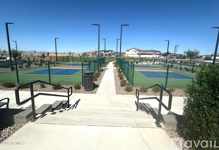 Tennis courts surrounded by green fence and bushes.