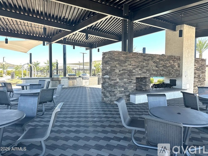 A patio with tables and chairs and a stone fireplace.