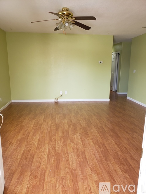 A room with a ceiling fan and wooden flooring.