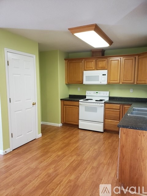A kitchen with a white stove and wooden cabinets.