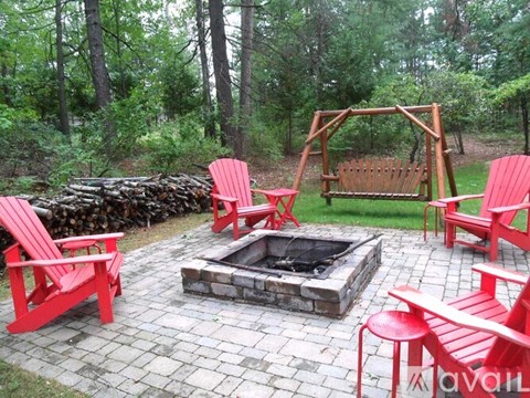 A fire pit surrounded by red chairs in a backyard.